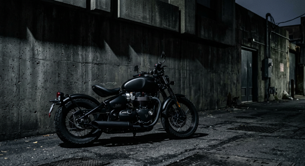 A matte black motorcycle parked against a dark, minimalist concrete wall in an urban architectural s
